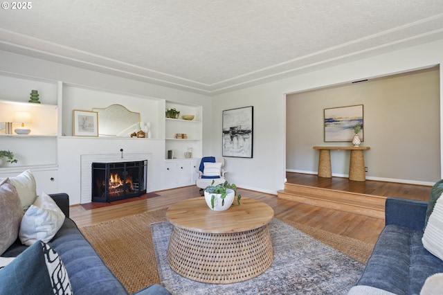 17787 Kelok Rd, Lake Oswego, OR 97034 - living room featuring a textured ceiling, a fireplace, wood finished floors, built in features, and baseboards