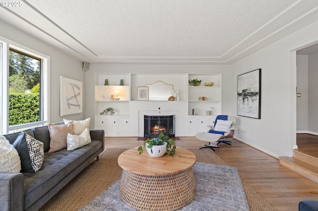 17787 Kelok Rd, Lake Oswego, OR 97034 - living room with a textured ceiling, built in features, wood finished floors, a lit fireplace, and baseboards