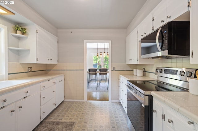 17787 Kelok Rd, Lake Oswego, OR 97034 - kitchen with stainless steel electric range oven, open shelves, white cabinetry, tile countertops, and tile walls