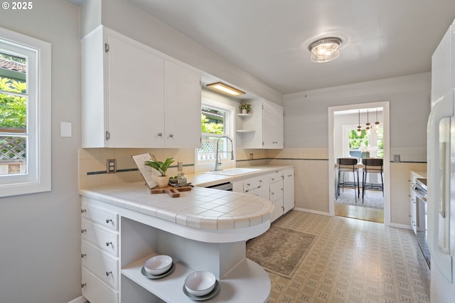 17787 Kelok Rd, Lake Oswego, OR 97034 - kitchen with open shelves, a sink, white cabinetry, a peninsula, and tile walls