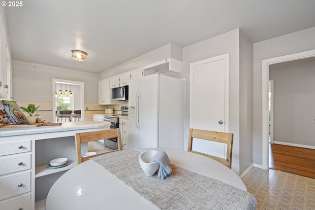 17787 Kelok Rd, Lake Oswego, OR 97034 - kitchen with stainless steel appliances, white cabinets, tile counters, and baseboards