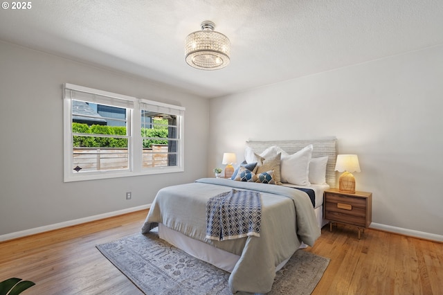 17787 Kelok Rd, Lake Oswego, OR 97034 - bedroom with baseboards, wood finished floors, a chandelier, and a textured ceiling