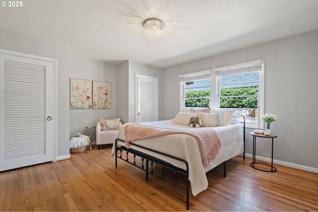 17787 Kelok Rd, Lake Oswego, OR 97034 - bedroom featuring light wood-style flooring, baseboards, a chandelier, and a textured ceiling