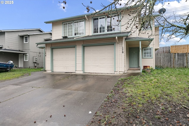 traditional-style home with an attached garage, fence, and concrete driveway