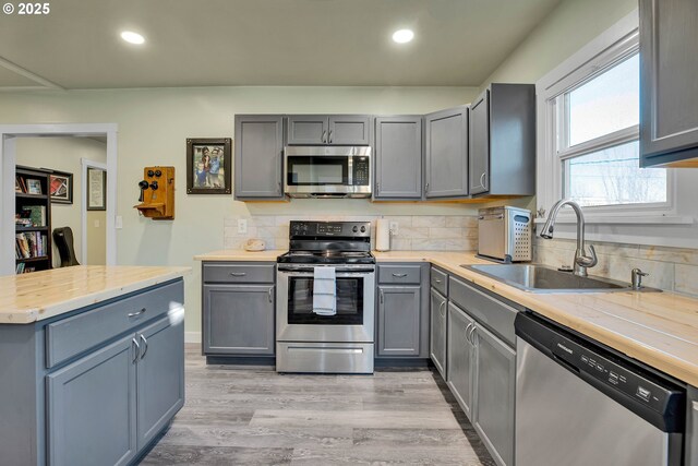 kitchen featuring light wood-type flooring, appliances with stainless steel finishes, sink, and gray cabinetry