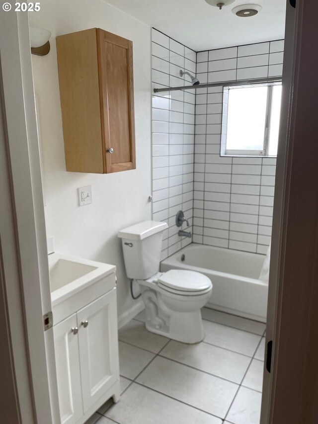 full bathroom with tile patterned flooring, tiled shower / bath, vanity, and toilet