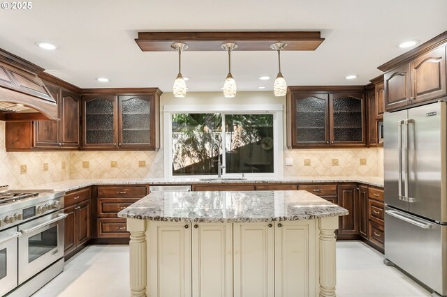 kitchen featuring premium appliances, pendant lighting, dark brown cabinetry, and a sink