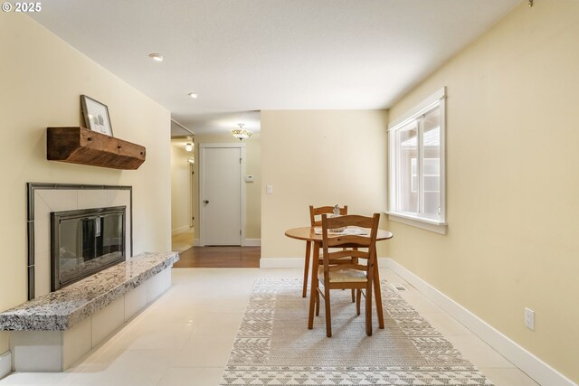 dining room with baseboards, a tiled fireplace, and light tile patterned floors