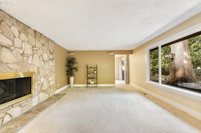 unfurnished living room featuring baseboards, carpet, a stone fireplace, and visible vents