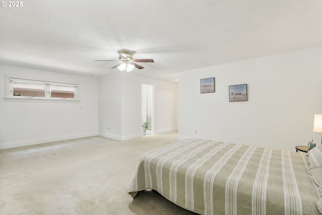 bedroom with a ceiling fan, baseboards, light colored carpet, and ensuite bath