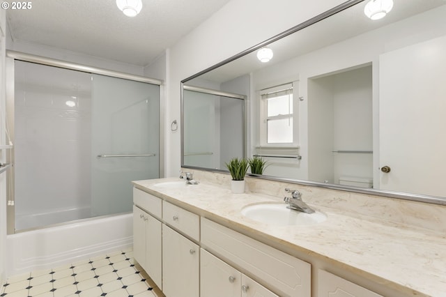 full bath with double vanity, tile patterned floors, combined bath / shower with glass door, and a sink