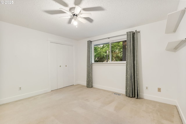 spare room with baseboards, a textured ceiling, ceiling fan, and light carpet