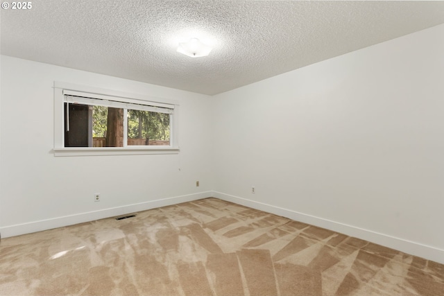 carpeted empty room featuring a textured ceiling, visible vents, and baseboards