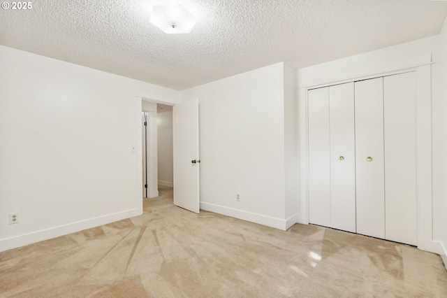 unfurnished bedroom featuring carpet floors, a textured ceiling, baseboards, and a closet