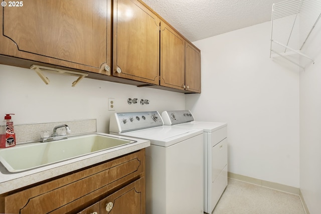 washroom featuring independent washer and dryer, cabinet space, a sink, a textured ceiling, and baseboards
