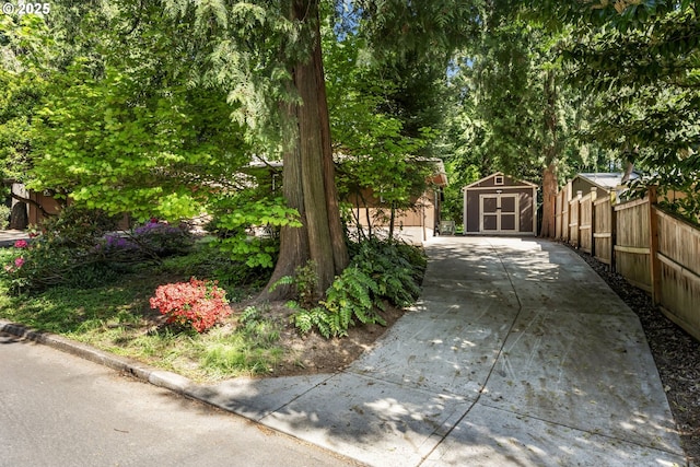 view of yard featuring a storage shed, fence, and an outdoor structure