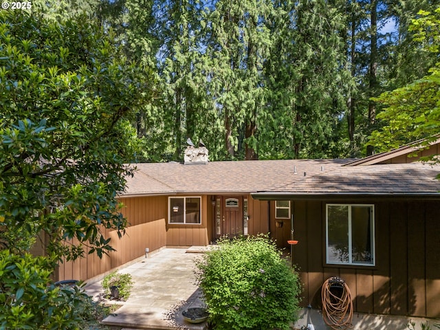 view of front of home featuring roof with shingles, board and batten siding, and a chimney
