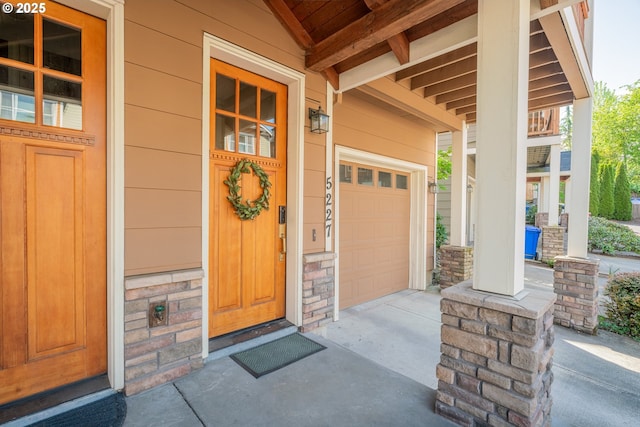 5227 SW Shattuck Rd, Portland, OR 97221 - property entrance featuring covered porch, stone siding, and concrete driveway