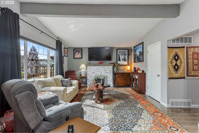 living room featuring visible vents, vaulted ceiling with beams, and wood finished floors