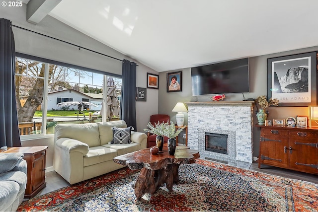 living area with a stone fireplace and vaulted ceiling with beams