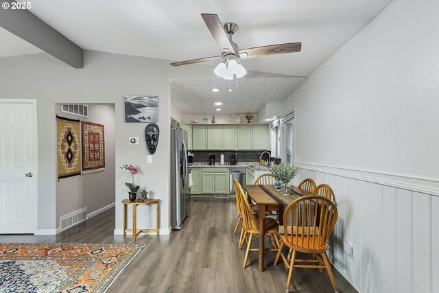 dining space featuring dark wood-style floors, visible vents, beam ceiling, and a wainscoted wall