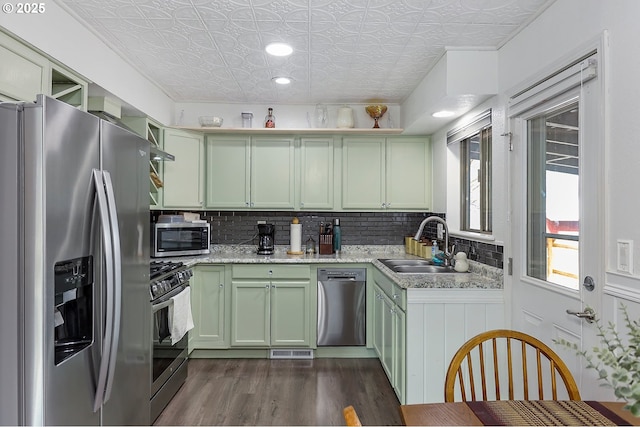 kitchen with green cabinetry, decorative backsplash, appliances with stainless steel finishes, an ornate ceiling, and a sink