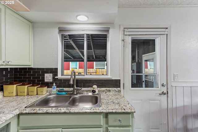 kitchen featuring tasteful backsplash, green cabinetry, light countertops, and a sink