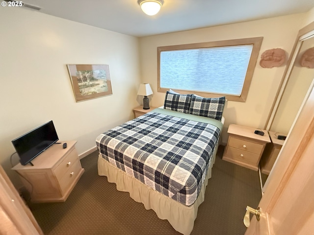 bedroom with dark colored carpet and baseboards