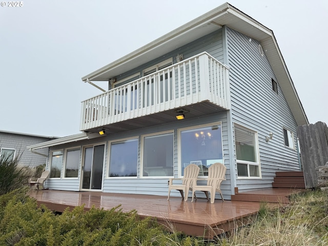 back of house featuring a balcony and a wooden deck