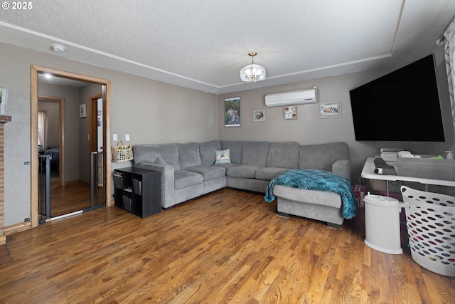 living room with wood-type flooring, a wall mounted AC, a textured ceiling, and a notable chandelier