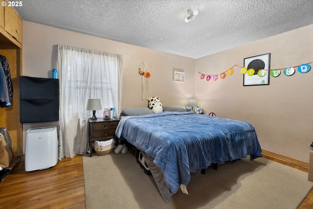 bedroom with hardwood / wood-style floors and a textured ceiling