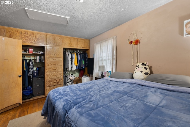 bedroom with dark wood-type flooring, a textured ceiling, and a closet