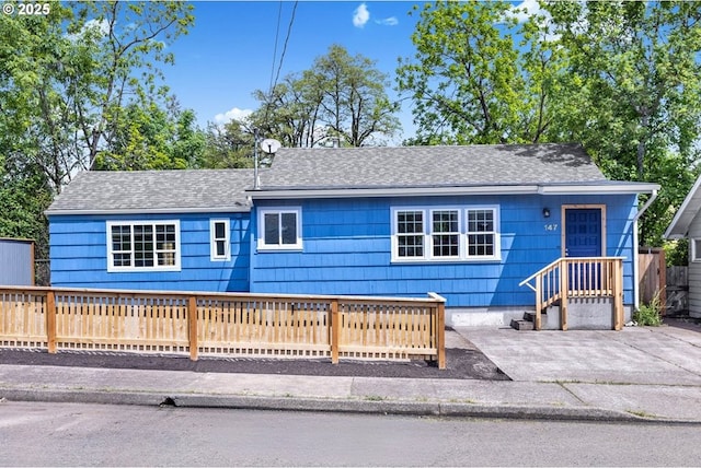 ranch-style house with roof with shingles and fence