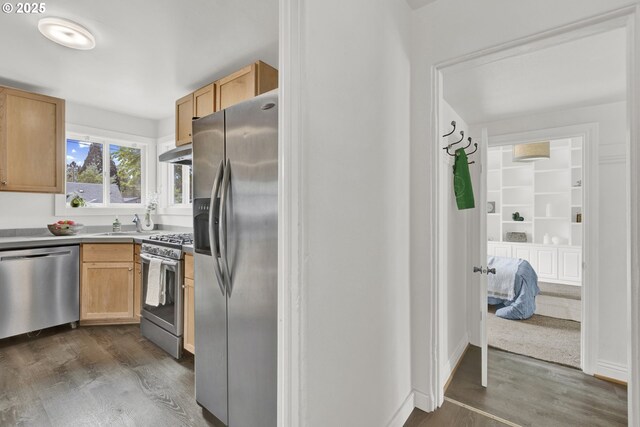 kitchen with appliances with stainless steel finishes, under cabinet range hood, and dark wood-style flooring