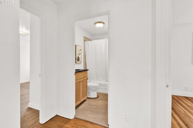 bathroom with vanity, wood finished floors, toilet, baseboards, and shower / bath combination with curtain