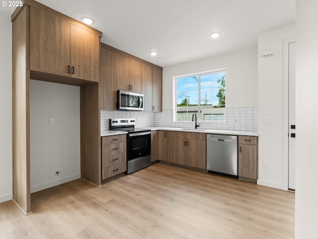 7586 N Alma Ave Unit 2, Portland, OR 97203 - kitchen featuring stainless steel appliances, a sink, light countertops, light wood-style floors, and tasteful backsplash
