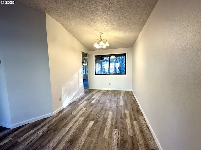 unfurnished dining area featuring lofted ceiling, a textured ceiling, dark wood-type flooring, and a chandelier