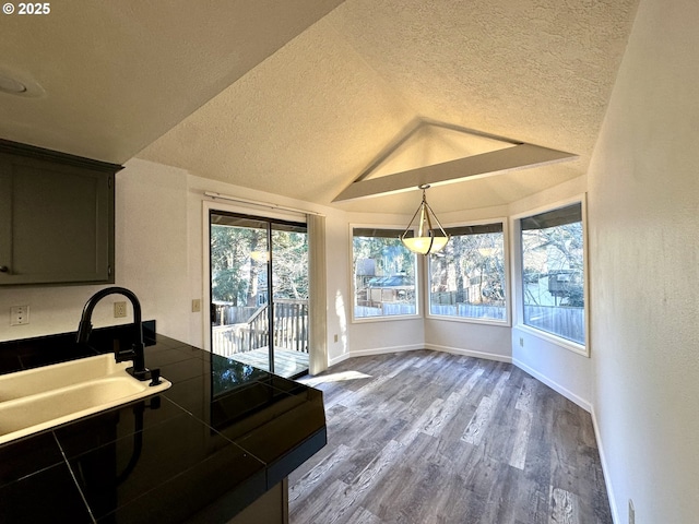 kitchen featuring lofted ceiling, sink, tile counters, pendant lighting, and hardwood / wood-style floors