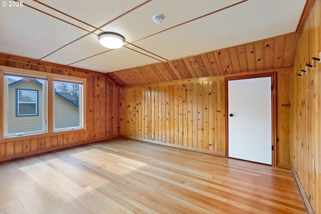additional living space with wood walls, baseboards, light wood finished floors, and lofted ceiling