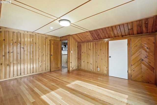 unfurnished room with wood walls and light wood-type flooring