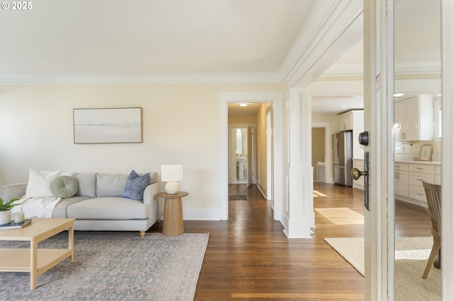 living area featuring dark wood finished floors, baseboards, crown molding, and ornate columns