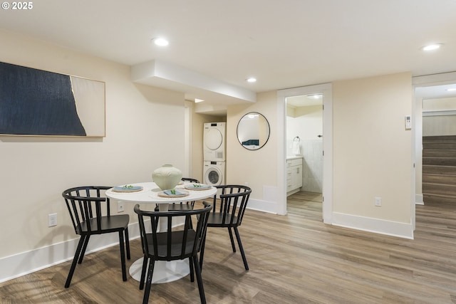 dining space featuring baseboards, stacked washer and clothes dryer, wood finished floors, and stairs