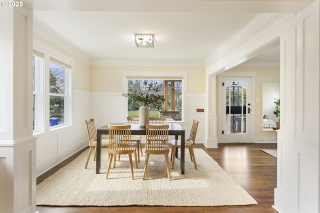 dining area featuring a wealth of natural light, a decorative wall, and dark wood-style floors