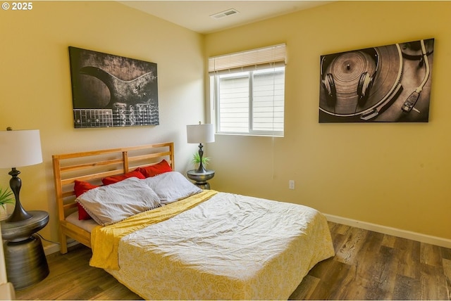 bedroom with wood finished floors, visible vents, and baseboards