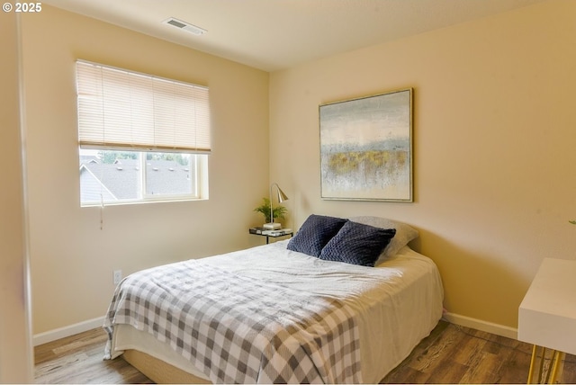 bedroom with baseboards, wood finished floors, and visible vents