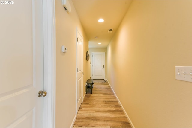 hallway featuring baseboards, recessed lighting, and light wood-style floors