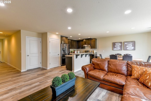 living room featuring visible vents, light wood-style flooring, baseboards, and recessed lighting