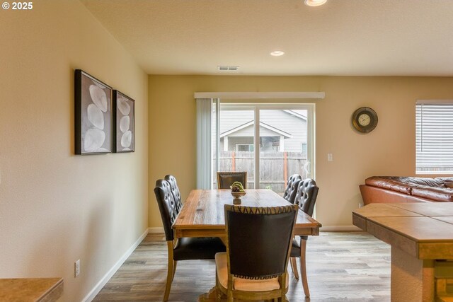 dining space featuring wood finished floors, visible vents, and baseboards