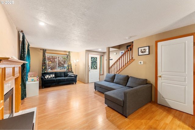 3929 SE 117th Pl, Portland, OR 97266 - living area with light wood finished floors, a textured ceiling, stairs, a tiled fireplace, and recessed lighting