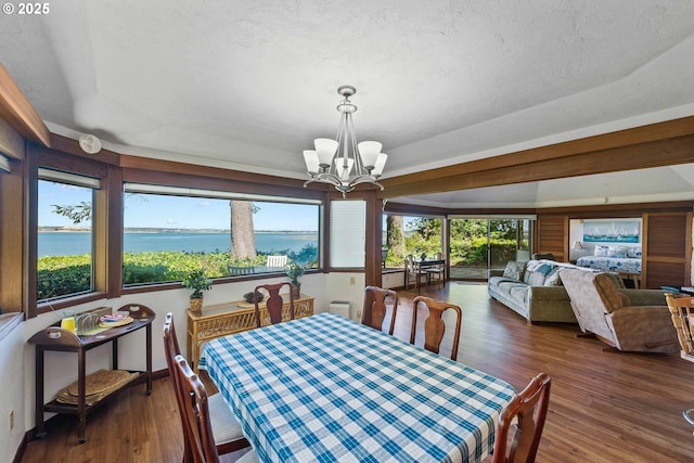 1230 Seagate Ave, Coos Bay, OR 97420 - dining room with a chandelier, wood finished floors, a water view, and a textured ceiling